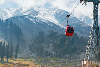 a red cable car going up a mountain side