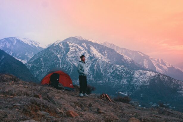 a man standing next to a tent on a mountain