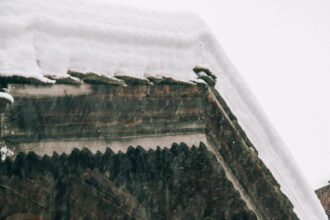 Wooden cottage with burning lantern during snowfall