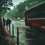 a group of people walking down a sidewalk next to a bus