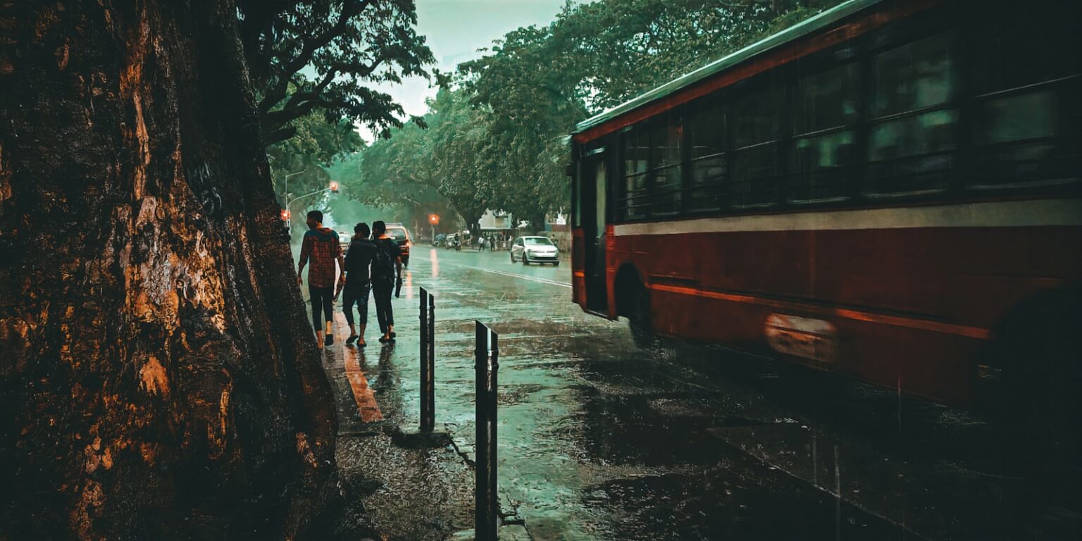 a group of people walking down a sidewalk next to a bus