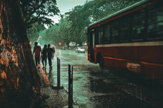 a group of people walking down a sidewalk next to a bus